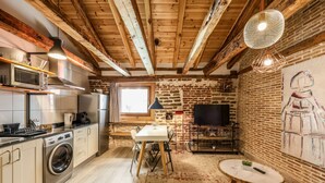 A rustic kitchen with wooden beams, a dining table, and a TV in a cozy room. - Beautiful Renovated apartment in the center 2  (Madrid)