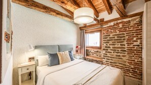 A bedroom with a bed, nightstand, lamp, and a brick wall. - Beautiful Renovated apartment in the center 2  (Madrid)