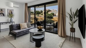 A modern living room with a sofa, coffee table, and a large window with curtains.