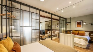 A modern hotel room with a large bed, a desk, a sofa, and a mirrored wall. - Design loft in CHUECA I3IZQ (Madrid)