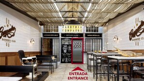A barbershop with a modern interior, featuring a central entrance marked by a red door, and a ceiling with a unique woven design. - Design loft in CHUECA I3IZQ (Madrid)
