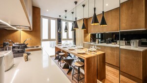 A modern kitchen with a central island, pendant lighting, and wooden cabinetry. - Design loft in CHUECA I2IZQ (Madrid)