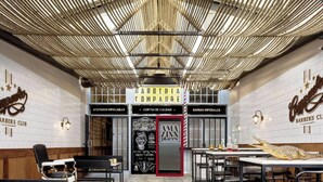 A barbershop with a modern interior, featuring a central entrance marked by a red door, and a ceiling with a unique woven design. - Design loft in CHUECA I2IZQ (Madrid)