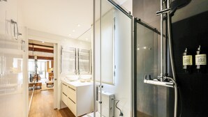 A modern bathroom with a glass shower enclosure, a white sink, and a toilet. - Design loft in CHUECA I4D (Madrid)