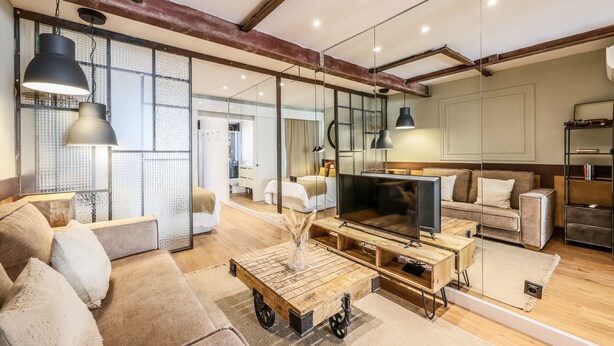 A modern living room with a large flat-screen TV, a coffee table with wheels, and a sofa. - Design loft in CHUECA I4D (Madrid)