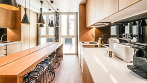 A modern kitchen with wooden cabinets, a long countertop, and black pendant lights. - Design loft in CHUECA I4D (Madrid)
