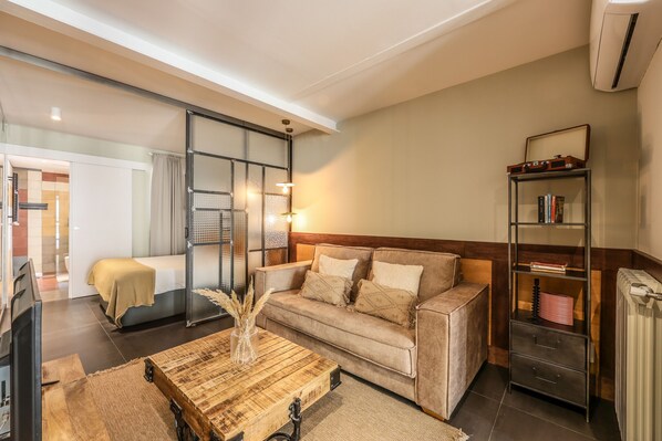 A modern living room with a sofa, coffee table, and a bookshelf. - Design loft in CHUECA I4I (Madrid)