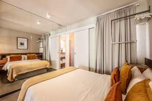 A hotel room with two beds, a large mirror, a wardrobe, and a view of the bathroom. - Design loft in CHUECA I4I (Madrid)