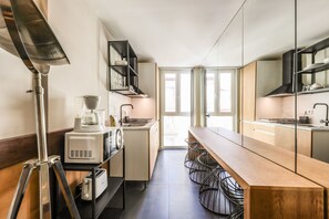 A modern kitchen with a long wooden countertop, built-in appliances, and a view to the outside. - Design loft in CHUECA I4I (Madrid)
