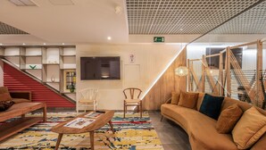 Een moderne lobby met een trap, zithoek en een receptiebalie.