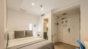 Een slaapkamer met een bed, een bureau en een stoel. Een deur leidt naar de badkamer.