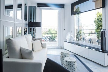 living room, with designed sofa and furniture, a television and views of the apartment's terrace.