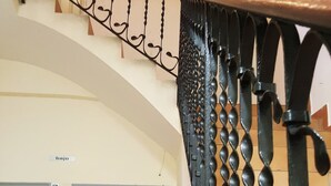 Una escalera con barandillas de metal ornamentadas y una puerta azul con la etiqueta 'a'.