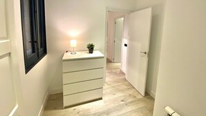 A narrow hallway with a white dresser, a small plant, and a lamp. - Incredible apartment in Atocha, 1C (Madrid)