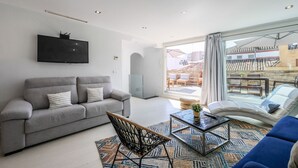 A modern living room with a grey sofa, a blue sofa, a coffee table, and a TV mounted on the wall. - Penthouse with solarium  in Plaza Mayor and Sol (Madrid)