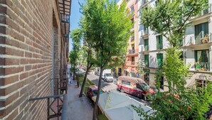 Une rue étroite, bordée de bâtiments des deux côtés, avec une voiture garée et un autobus.
