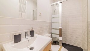 Une salle de bain moderne avec un grand lavabo blanc, une douche en verre et des toilettes.