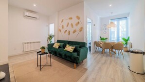 Un salon moderne avec un canapé vert, une petite table d’appoint et un coin repas comprenant une table et des chaises.