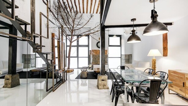 A modern dining area with a glass table, black chairs, and pendant lighting.