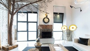 A modern living room with a fireplace, a large window, and a tree.