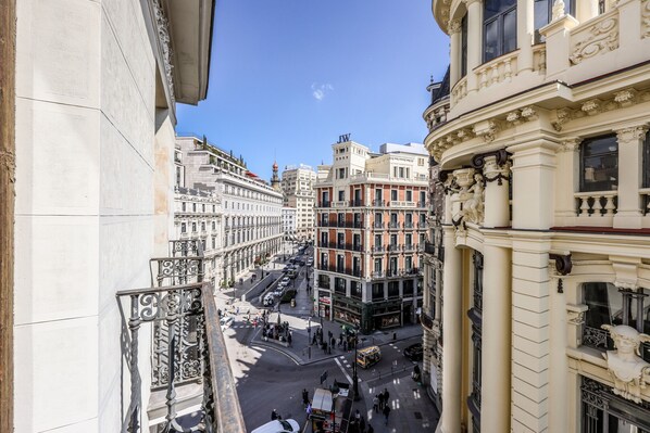 A street view with buildings featuring classical architecture, a clear sky, and a busy intersection.