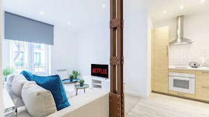Un salon moderne avec un canapé, une table basse et un téléviseur affichant le logo « NETFLIX ».
