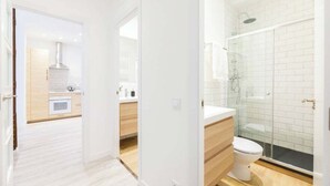 Une salle de bain moderne avec une douche à parois de verre, des toilettes blanches et un meuble-lavabo en bois.