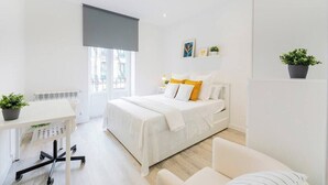 Une chambre à coucher moderne, avec un lit, une table de chevet et un bureau avec une chaise.