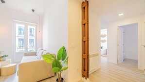 A modern living room with a sofa, a potted plant, and a wooden ladder against the wall.