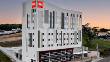 A modern hotel with a white facade, multiple windows, and a red accent at the bottom.