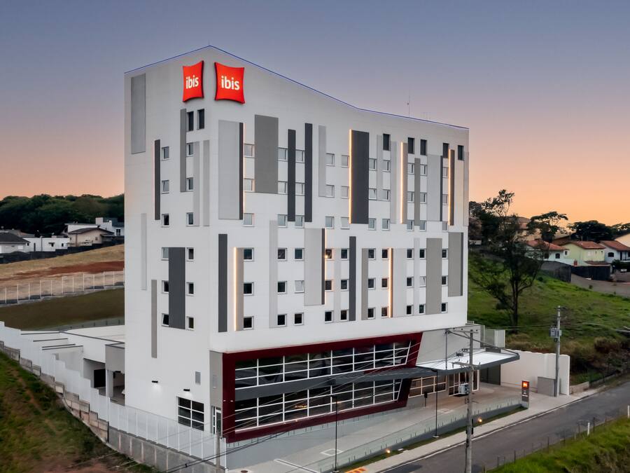 A modern hotel with a white facade, multiple windows, and a red accent at the bottom.