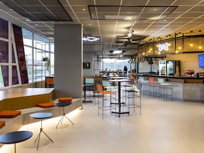 Um café moderno com área de bar, assentos dispostos e vista através de grandes janelas.