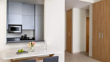 A modern kitchen with a built-in microwave, a coffee maker, and a dining area with two chairs and a table.
