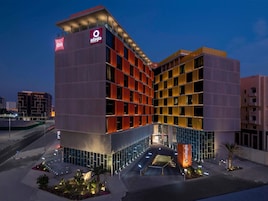 Un hotel moderno con un llamativo letrero 'Adagio', con una estructura de varios pisos que combina paneles de vidrio y sólidos, y un área de entrada bien iluminada.