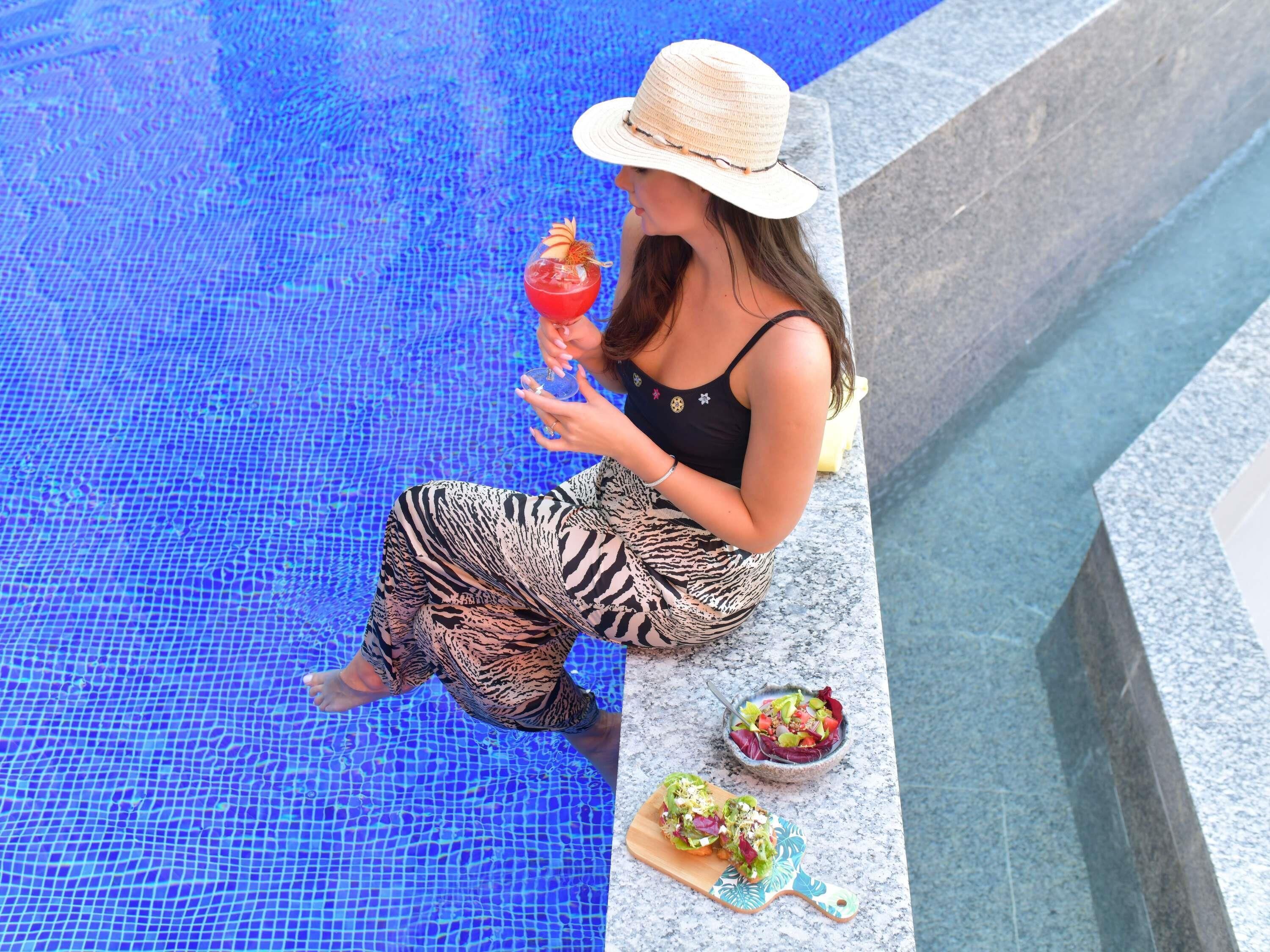 Una piscina al aire libre, sombrillas, sillones reclinables de piscina