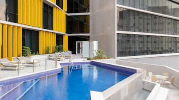Una piscina al aire libre, sombrillas, sillones reclinables de piscina