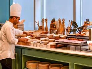 A buffet setup with various food items and serving utensils. - Ibis Doha (Doha)