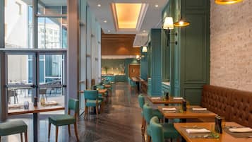 A modern restaurant interior with high ceilings, large windows, and a mix of seating arrangements including tables and booths.