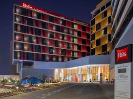 Un hotel moderno con una fachada llamativa de color rojo y amarillo, amplias ventanas y una entrada bien iluminada.