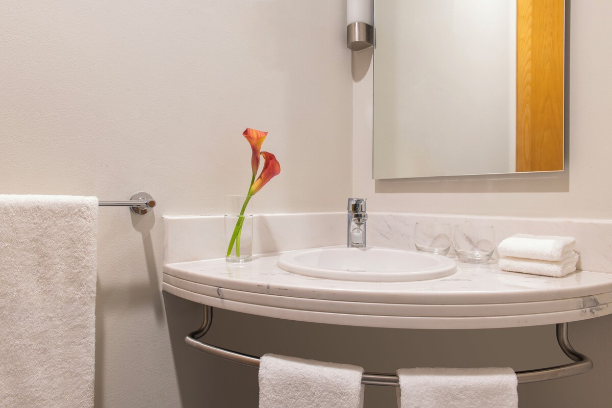 A bathroom with a white sink, a mirror, and two towels hanging on a rack.