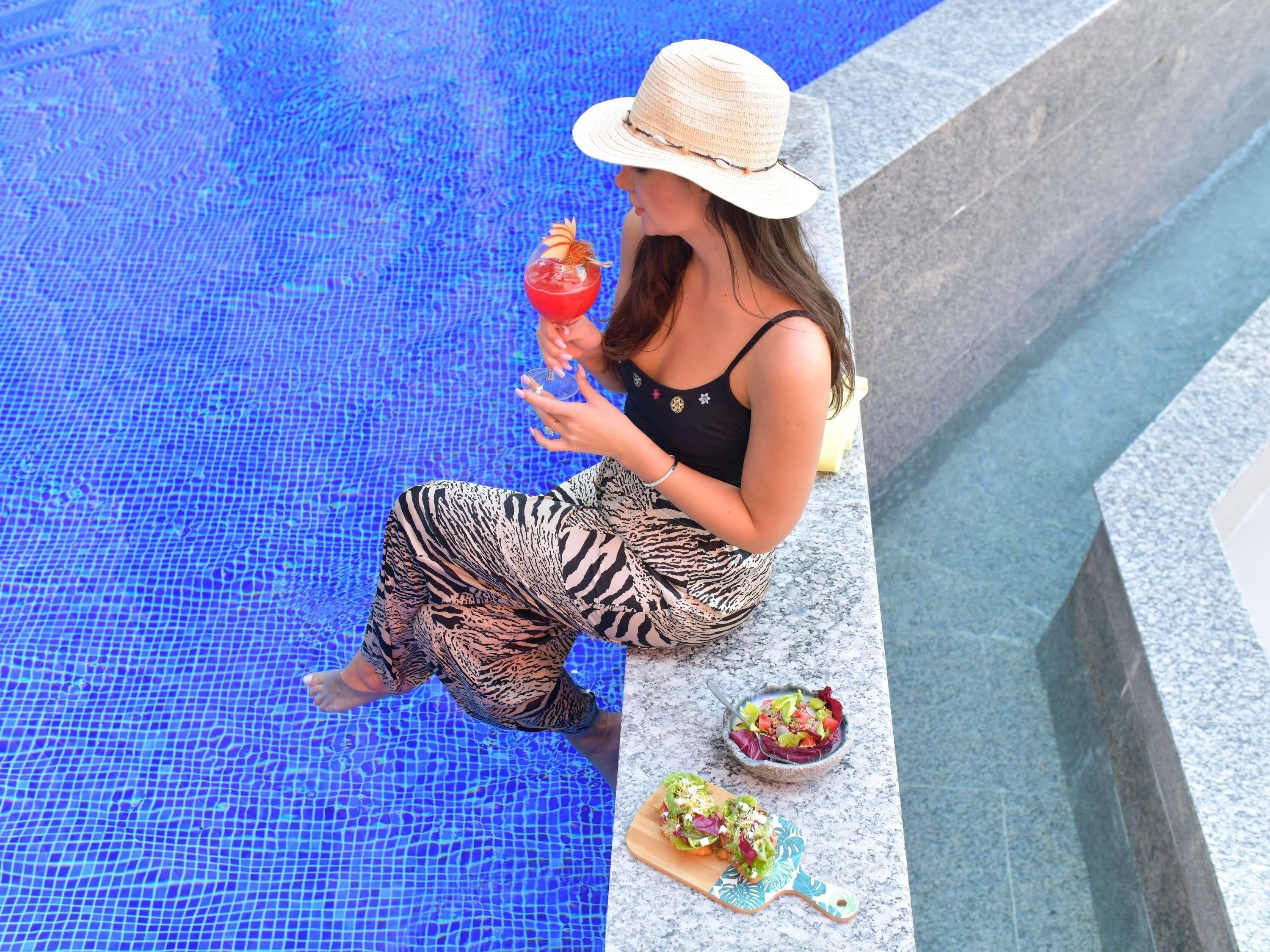 Una piscina al aire libre, sombrillas, sillones reclinables de piscina