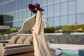 A person walking by a pool with a modern building in the background.