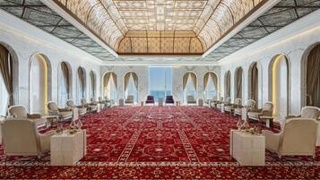 A luxurious hotel room with a large red carpet, marble walls, and a high ceiling with intricate designs.