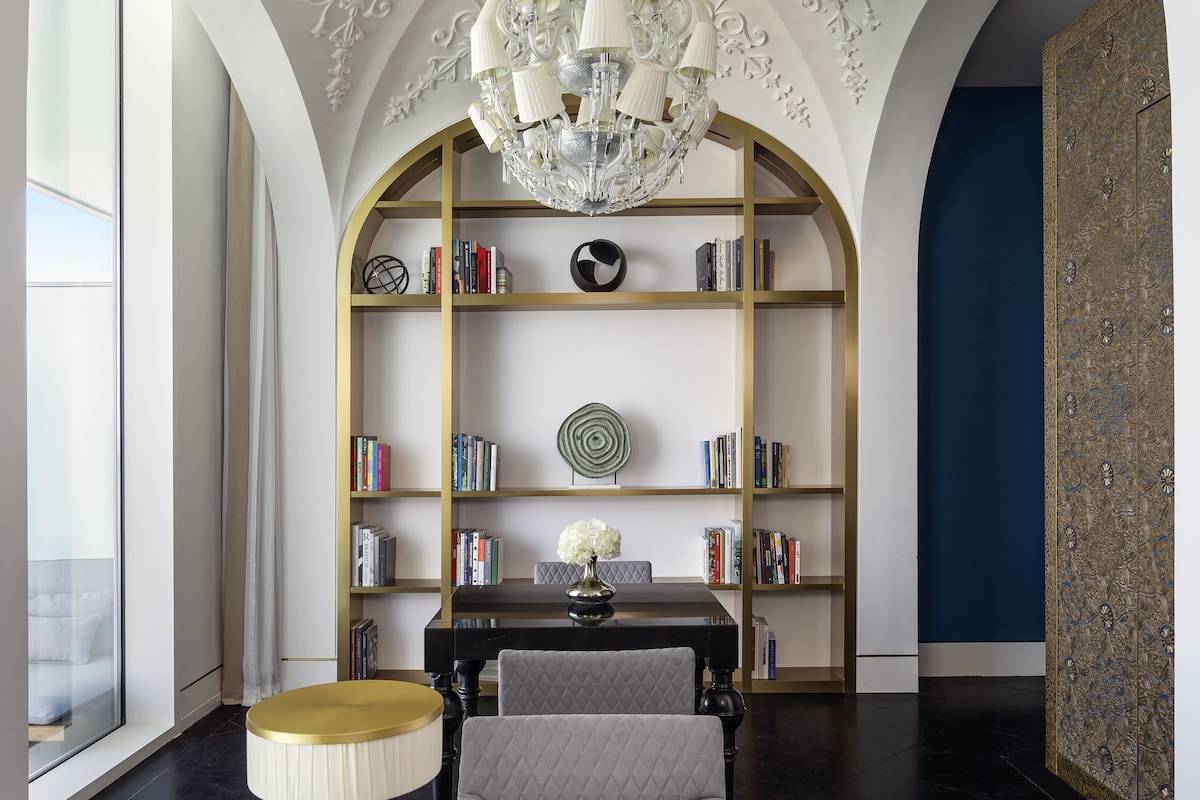 A modern interior with a chandelier, bookshelves, and a dining table.