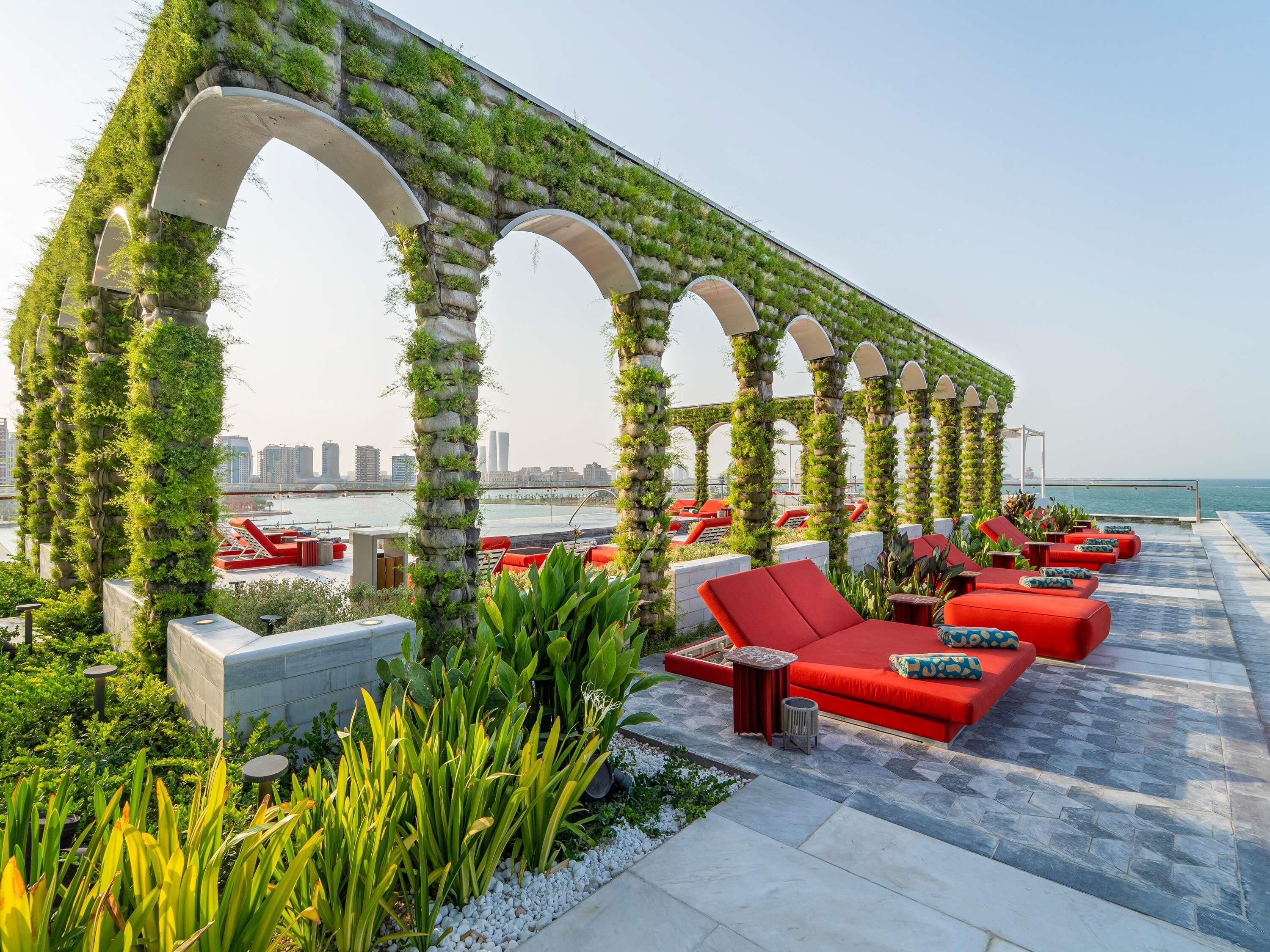 A rooftop lounge with red seating and a view of the city skyline.