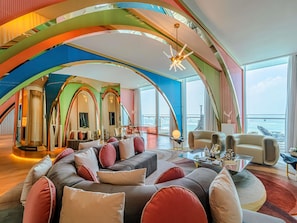 A spacious living area with a curved ceiling, a large sofa set, a coffee table, and a view of the sea.