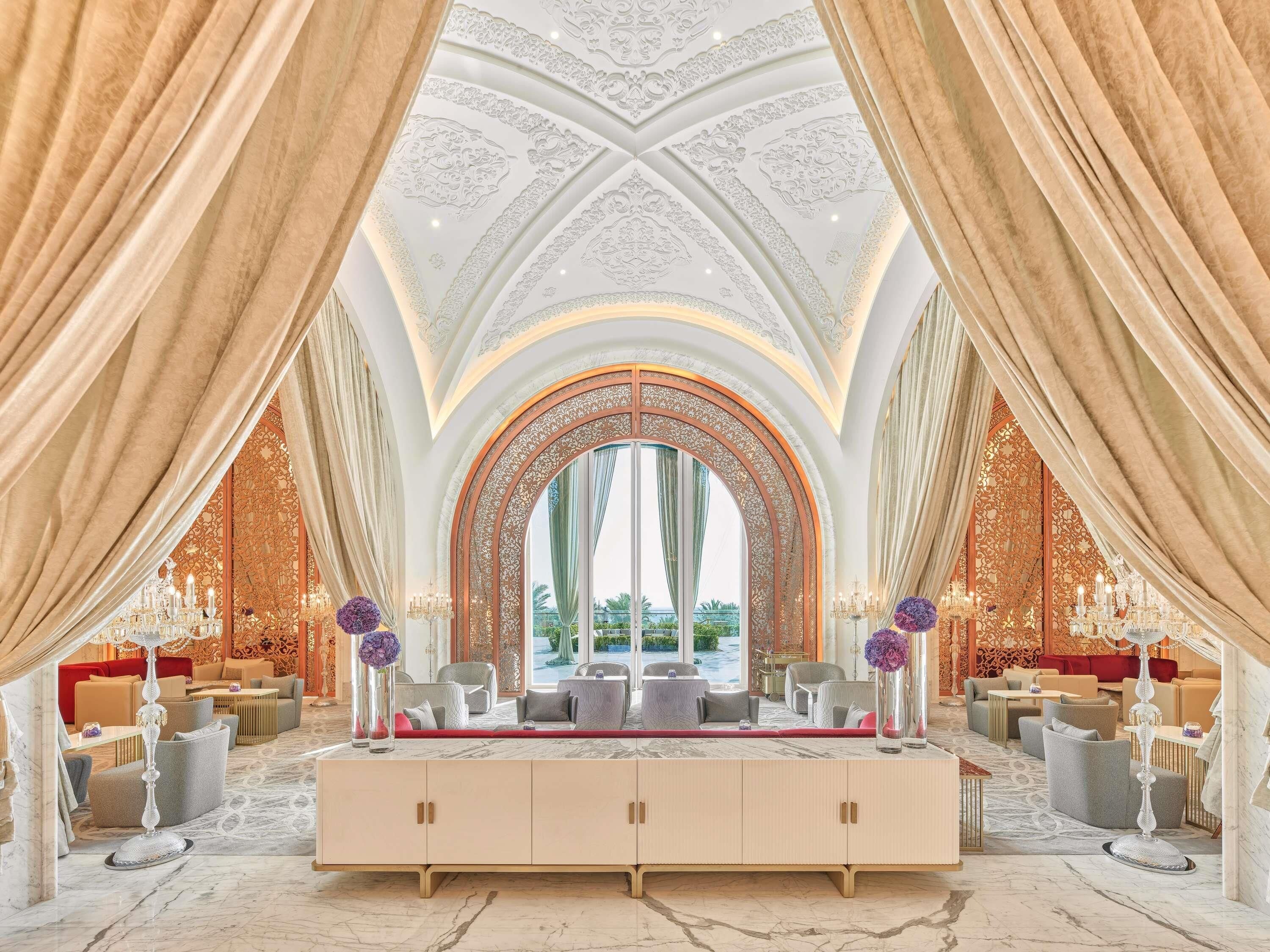 A luxurious interior with a grand arched mirror, elegant seating, and a marble floor.