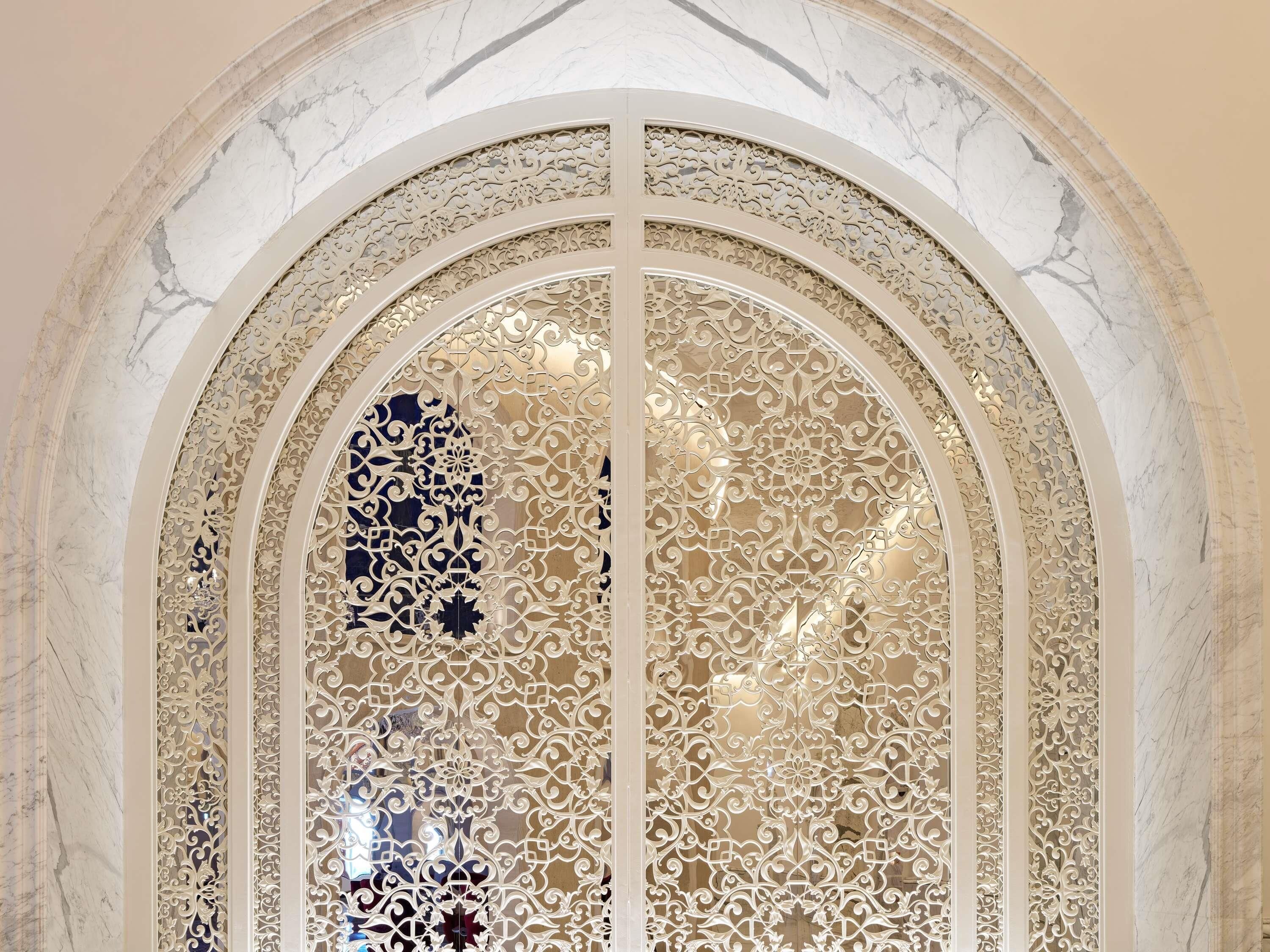 An arched doorway with intricate white decorative patterns and a marble-like background.