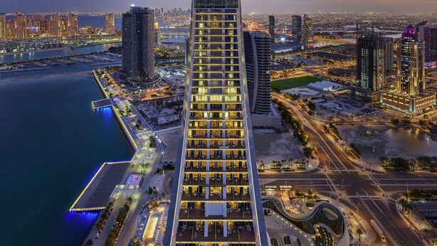 A high-rise hotel with a distinctive U-shaped top, multiple floors, and a waterfront view. - Raffles Doha (Doha)