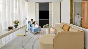 Una sala de estar moderna con un sofá, un sillón azul, una mesa de centro y un televisor.